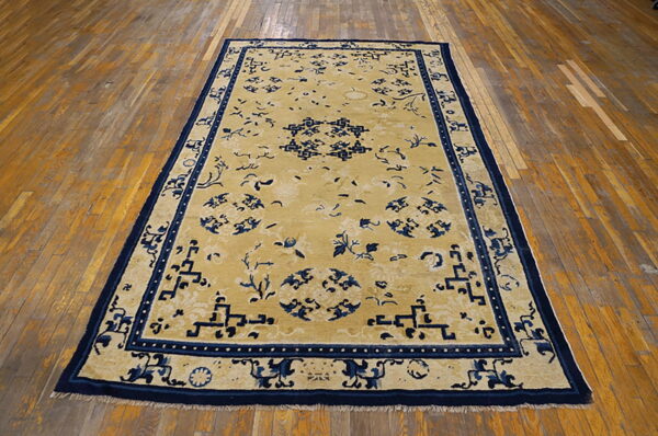Yellow rug featuring a bold navy blue oriental pattern and large geometric border on hardwood flooring.