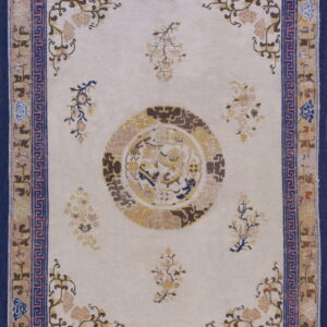 Off-white rug with a central gold medallion and scattered florals framed by blue Greek key and navy borders.