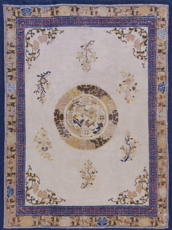Off-white rug with a central gold medallion and scattered florals framed by blue greek key and navy borders.