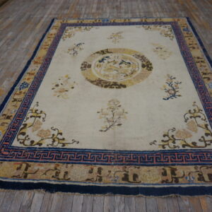 Low-pile rug with a cream field, yellow medallion, and a wide blue patterned border on wood floor.