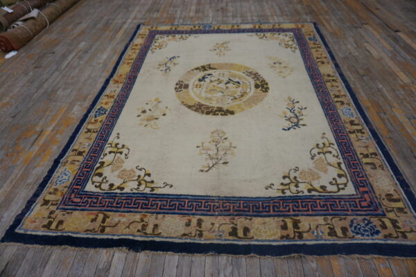 Low-pile rug with a cream field, yellow medallion, and a wide blue patterned border on wood floor.