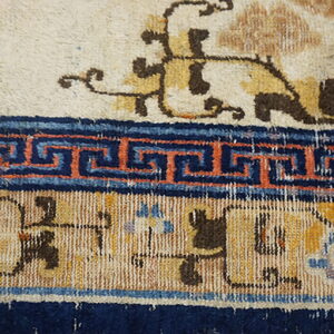 High pile rug detail showing cream, yellow, navy, and terracotta borders with floral and fret patterns.