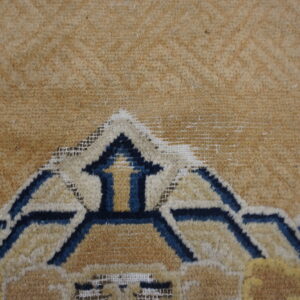 Geometric rug detail featuring dark blue and cream stylized arch shapes on a tan background.