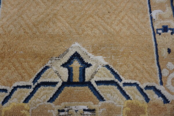 Geometric rug detail featuring dark blue and cream stylized arch shapes on a tan background.
