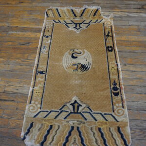 Tan runner rug featuring a central white bird motif and navy blue geometric borders on distressed wood planks.