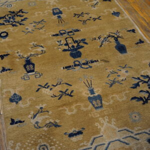 Tan rug with scattered navy blue motifs, including vases and flowers, laid on distressed wood planks.