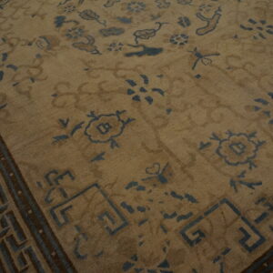 Muted beige rug with antique blue floral patterns and a dark brown geometric key border.