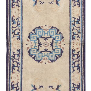 Narrow beige runner rug featuring scattered blue medallions and stylized motifs framed by a navy border.