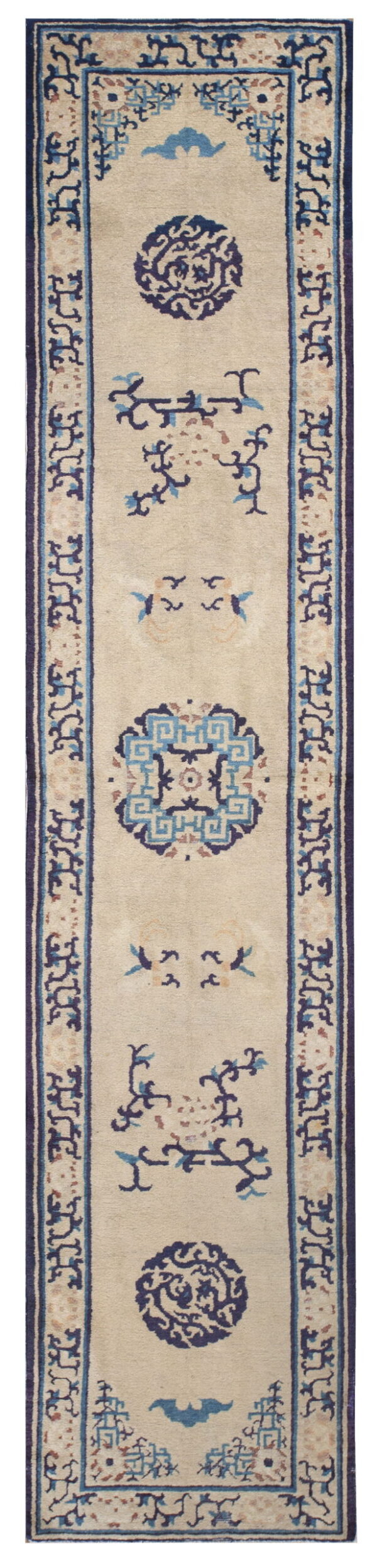 Narrow beige runner rug featuring scattered blue medallions and stylized motifs framed by a navy border.