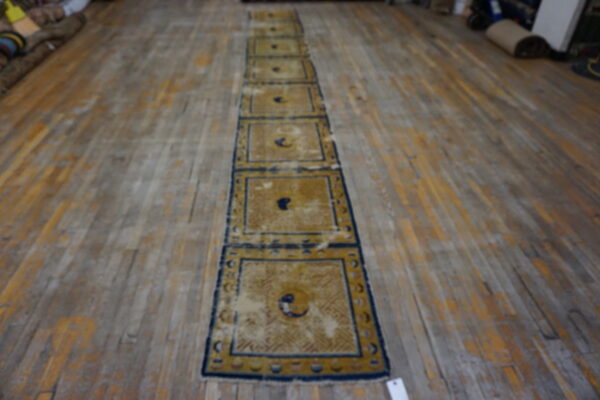 Yellow and blue runner rug with repeated panels displayed on rustic wood plank flooring.