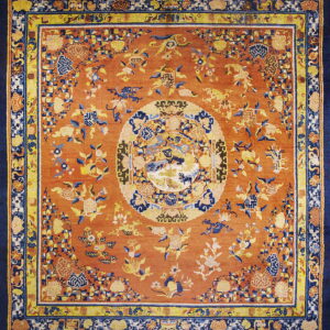 Terracotta rug with traditional yellow and blue floral designs and a contrasting navy main border.
