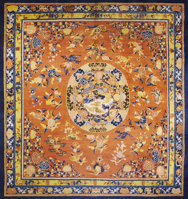 Terracotta rug with traditional yellow and blue floral designs and a contrasting navy main border.