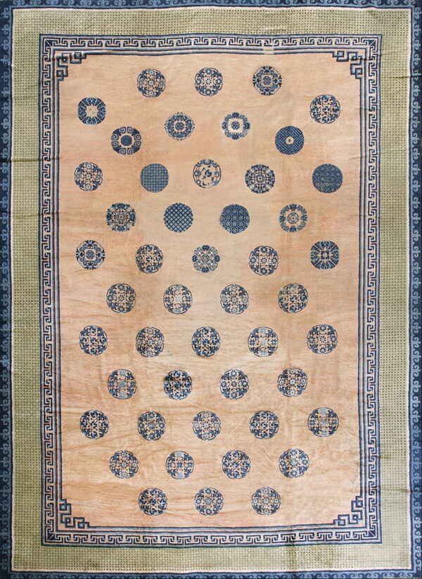 Beige rug with scattered blue medallions, framed by blue greek key and green geometric borders.