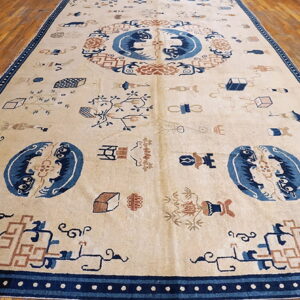 Large cream rug displaying blue and rust mythical figures and scatter motifs on wooden plank flooring.