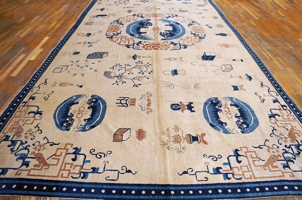 Large cream rug displaying blue and rust mythical figures and scatter motifs on wooden plank flooring.