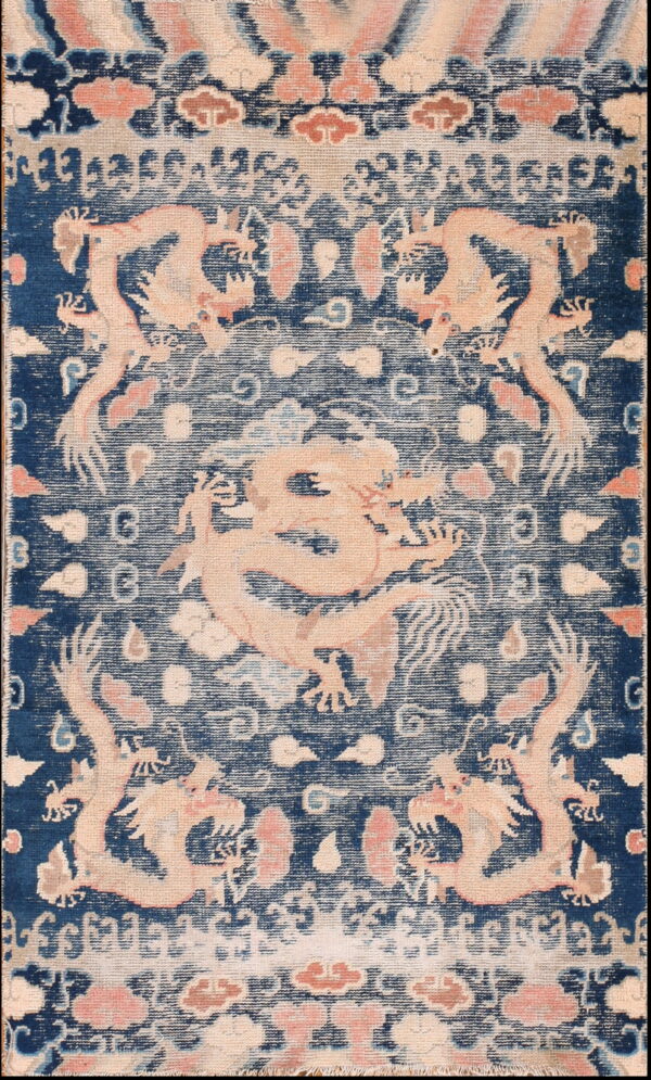 Dark blue rug featuring light pink dragon and cloud motifs in a detailed, distressed pattern.