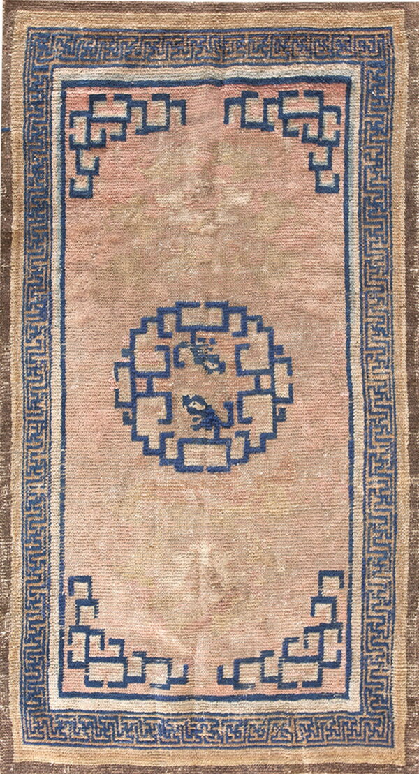 Pale rose and tan rug featuring a dark blue border and geometric interlocking patterns.
