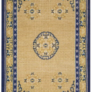 Low-pile golden rug with navy blue geometric borders and scattered light blue floral designs.
