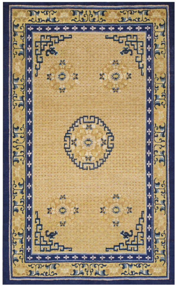 Low-pile golden rug with navy blue geometric borders and scattered light blue floral designs.