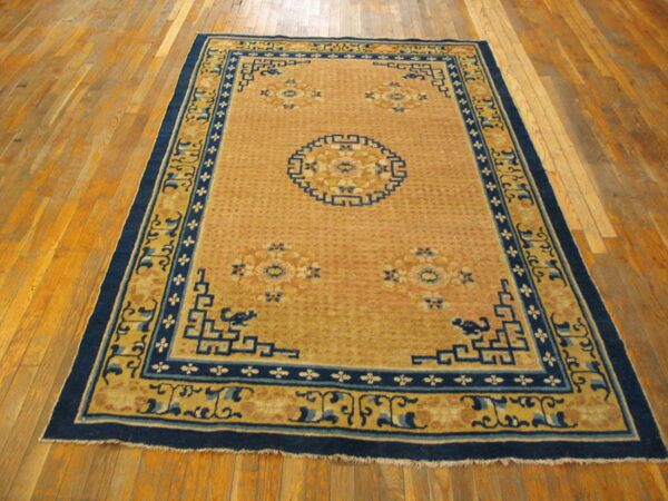 Saffron and blue geometric rug with a detailed central medallion displayed on light hardwood planks.