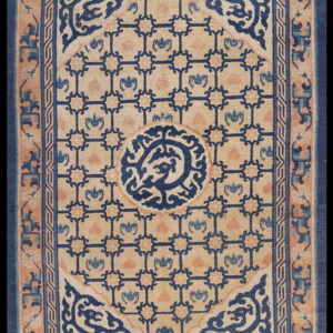 Beige rug with a dark blue geometric lattice and center medallion, bordered by peach and blue scrollwork.