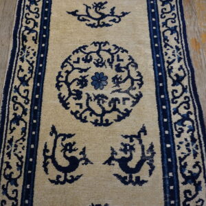 Beige runner rug featuring stylized dark blue medallions, mythological figures, and borders on wood planks.