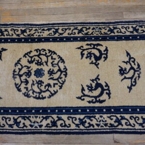 Tan and dark blue patterned runner rug with ornate borders rests on distressed wood flooring.