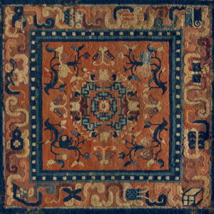 Textured orange rug featuring deep blue geometric and floral designs and multiple bordered frames.