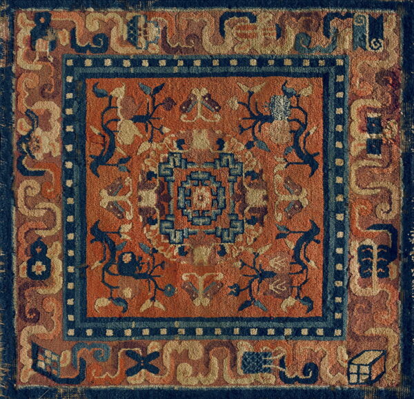 Textured orange rug featuring deep blue geometric and floral designs and multiple bordered frames.