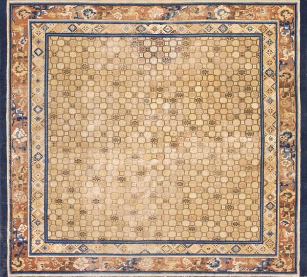 Beige rug with an interlocking geometric field and wide navy and terracotta floral border.