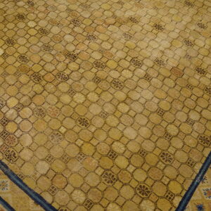 An aged yellow rug features a dense geometric lattice pattern outlined in brown, bordered by blue and terracotta stripes.