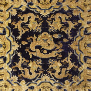 Intricate gold and dark blue rug with a symmetrical pattern of stylized dragons and figures.