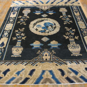 Navy blue and beige traditional rug featuring vases, scrolls, and a central mythical animal motif on wood floors.