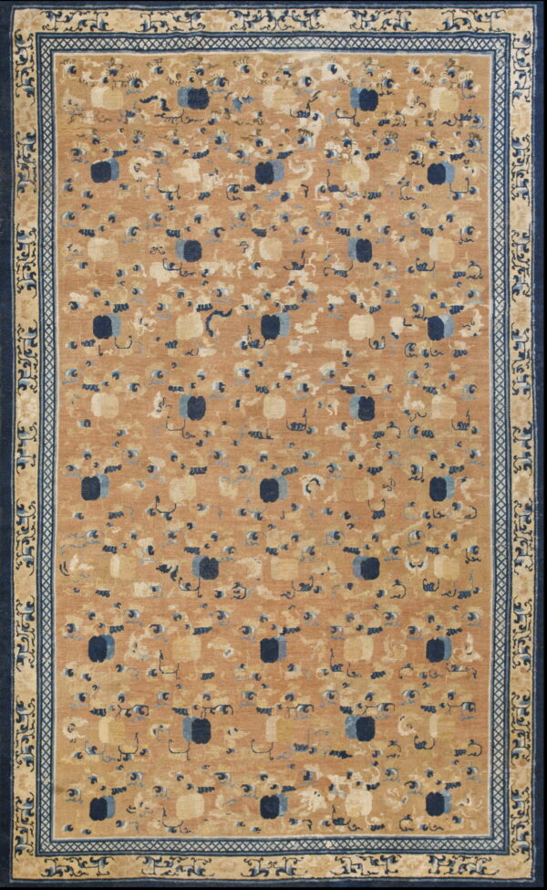 Tan rug featuring scattered stylized blue and cream patterns surrounded by layered ornate navy blue borders.
