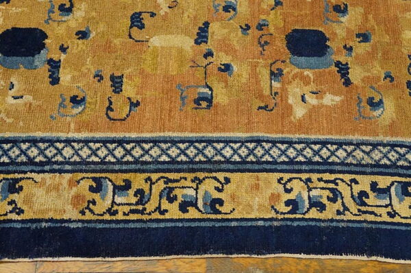 Saffron and navy patterned rug detail showing a geometric and scrolling border next to a low-pile field.