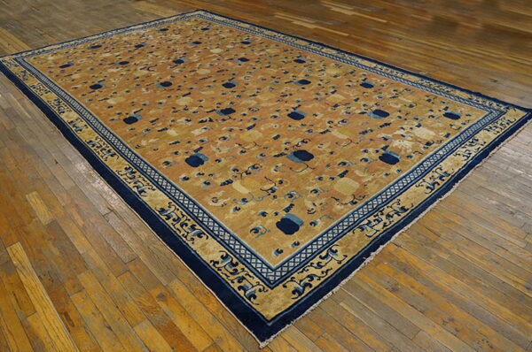 An ochre rug featuring a repeating cloud pattern and elaborate blue and gold borders sits on hardwood.