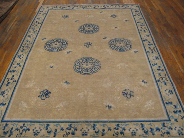 Beige area rug with indigo circular medallions and scrolling blue borders on warm hardwood flooring.