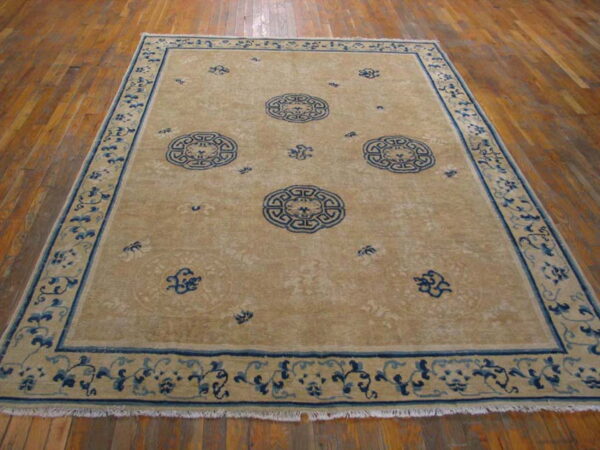 Low-pile tan rug with three central blue medallions and detailed floral borders on hardwood.