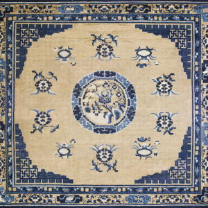 Tan rug with dark blue traditional Chinese-style floral sprays, a central medallion, and layered geometric borders.