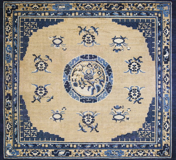 Tan rug with dark blue traditional chinese-style floral sprays, a central medallion, and layered geometric borders.
