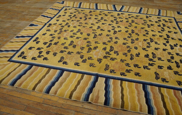 Yellow rug with scattered blue botanical motifs and a multi-colored wavy striped border on wood flooring.