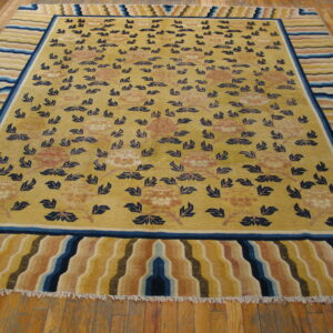 Yellow rug featuring scattered navy blue leaves and peach florals, bordered by wide, wavy colorful stripes.