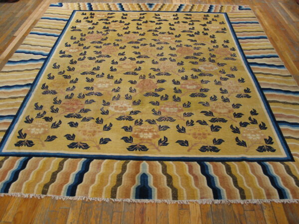 Yellow rug featuring scattered navy blue leaves and peach florals, bordered by wide, wavy colorful stripes.