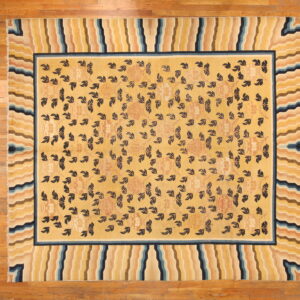 Yellow rug with dark foliage pattern and a wide border of wavy stripes in blue, tan, and yellow.