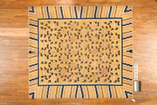 Yellow rug with dark foliage pattern and a wide border of wavy stripes in blue, tan, and yellow.