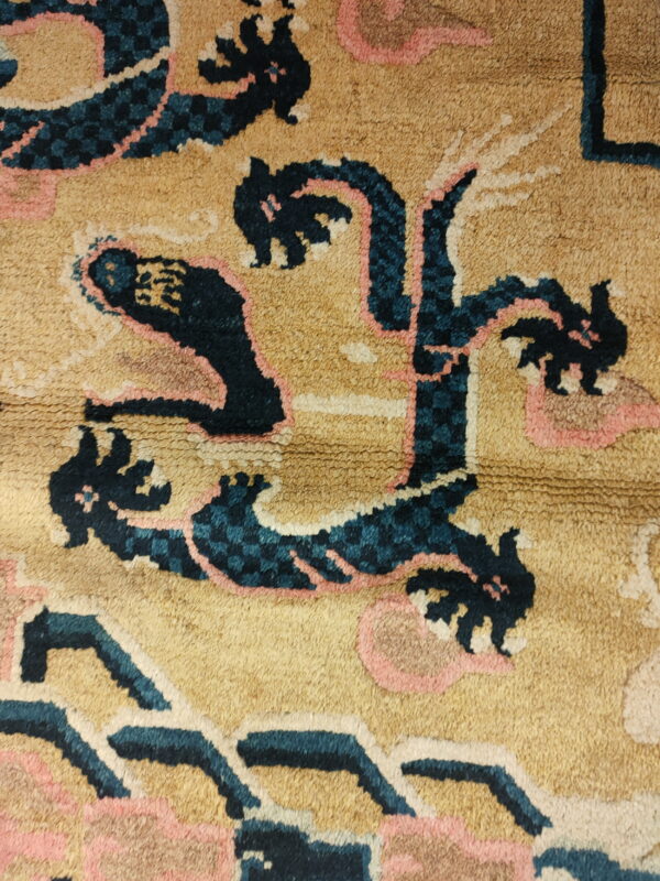 High-pile golden rug with large, stylized figures in dark blue, pink, and cream.