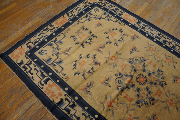 Antique chinese - ningxia small scatter size wool blue rug 5 Tan rug with floral and bird motifs, featuring a navy border, on distressed wood flooring.