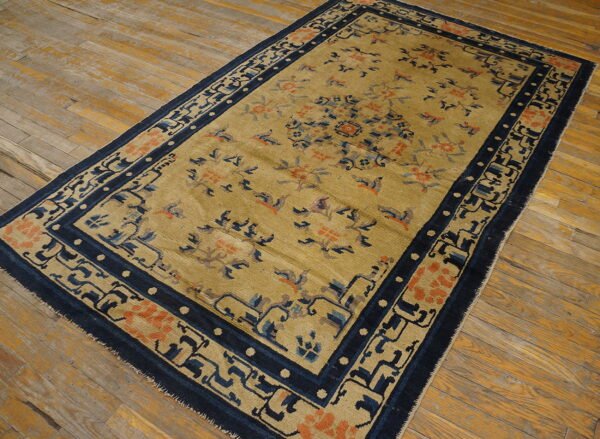 Antique chinese - ningxia small scatter size wool blue rug 4 Tan and orange floral rug with thick navy blue geometric borders lying on wide-plank wood floor.
