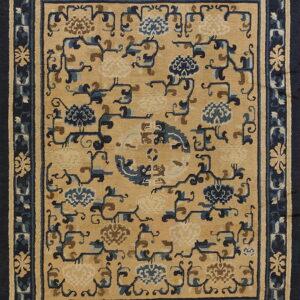 Tan rug with stylized blue and brown floral vines and a wide navy blue patterned border.