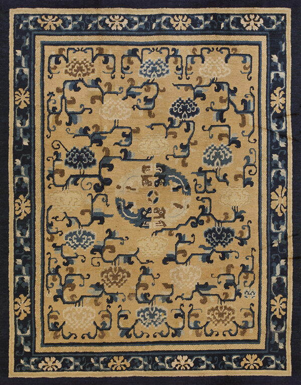 Tan rug with stylized blue and brown floral vines and a wide navy blue patterned border.